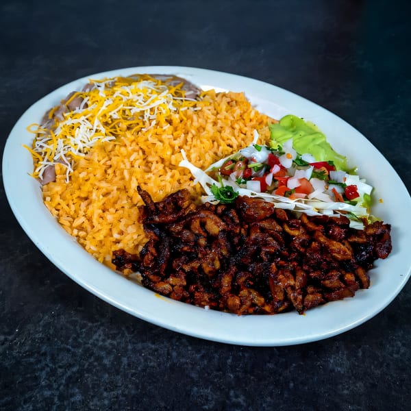 A Mexican dish with grilled meat, rice, beans with cheese, and a side salad on a white plate.