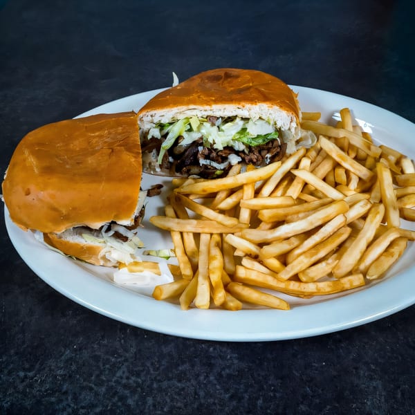 A Highlands D'Leon's Mexican torta sandwich, cut in half, with fries on a white plate.
